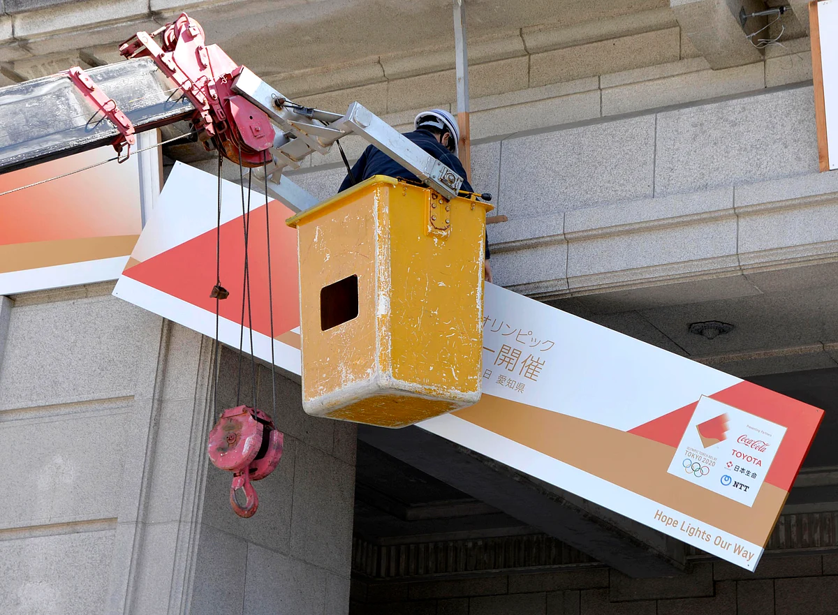 A board informing the Olympic torch relay is removed from the City Hall in Inazawa, Aichi Prefecture. The Olympics have been postponed by a year.