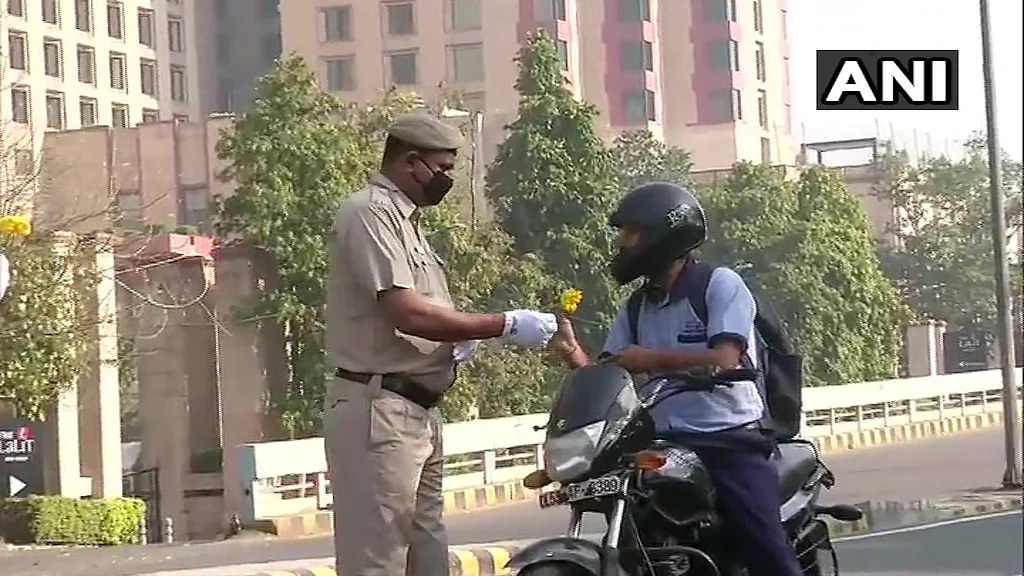 Delhi: Police personnel near Barakhamba Road offer flowers to the locals out on roads, requesting them to stay at home and observe the countrywide curfew.