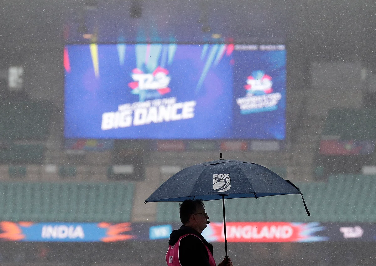 A worker stands under an umbrella as rain falls on the Sydney Cricket Ground delaying the start of the Women’s T20 World Cup cricket semifinal.