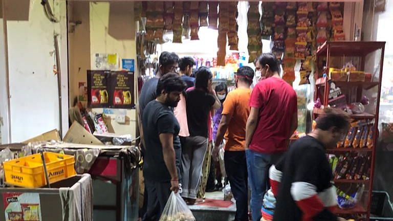 People  queue up to buy groceries.