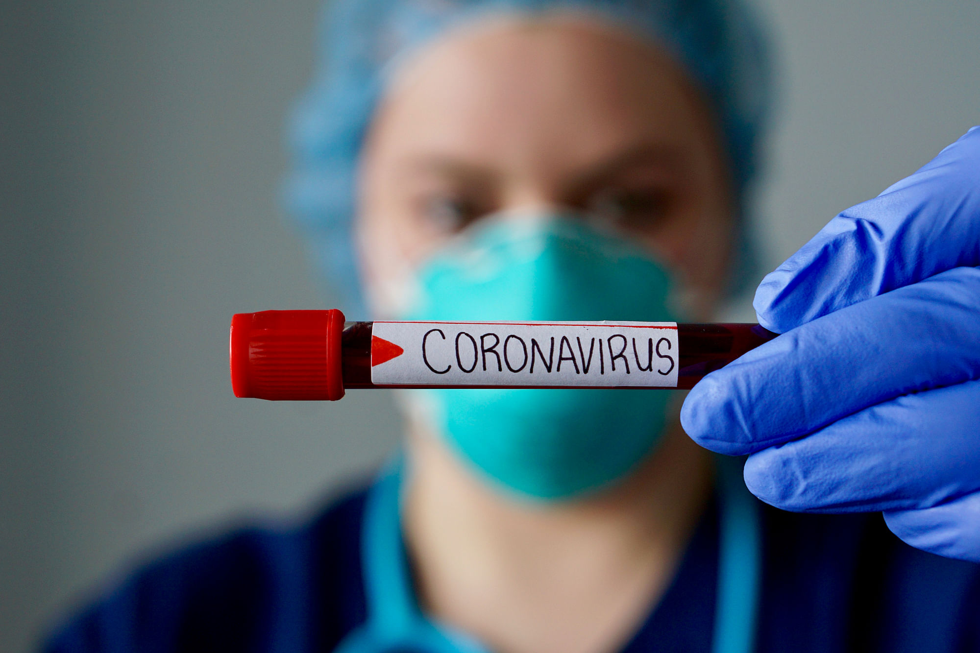 Nurse wearing respirator mask holding a positive blood test result for the new rapidly spreading Coronavirus.