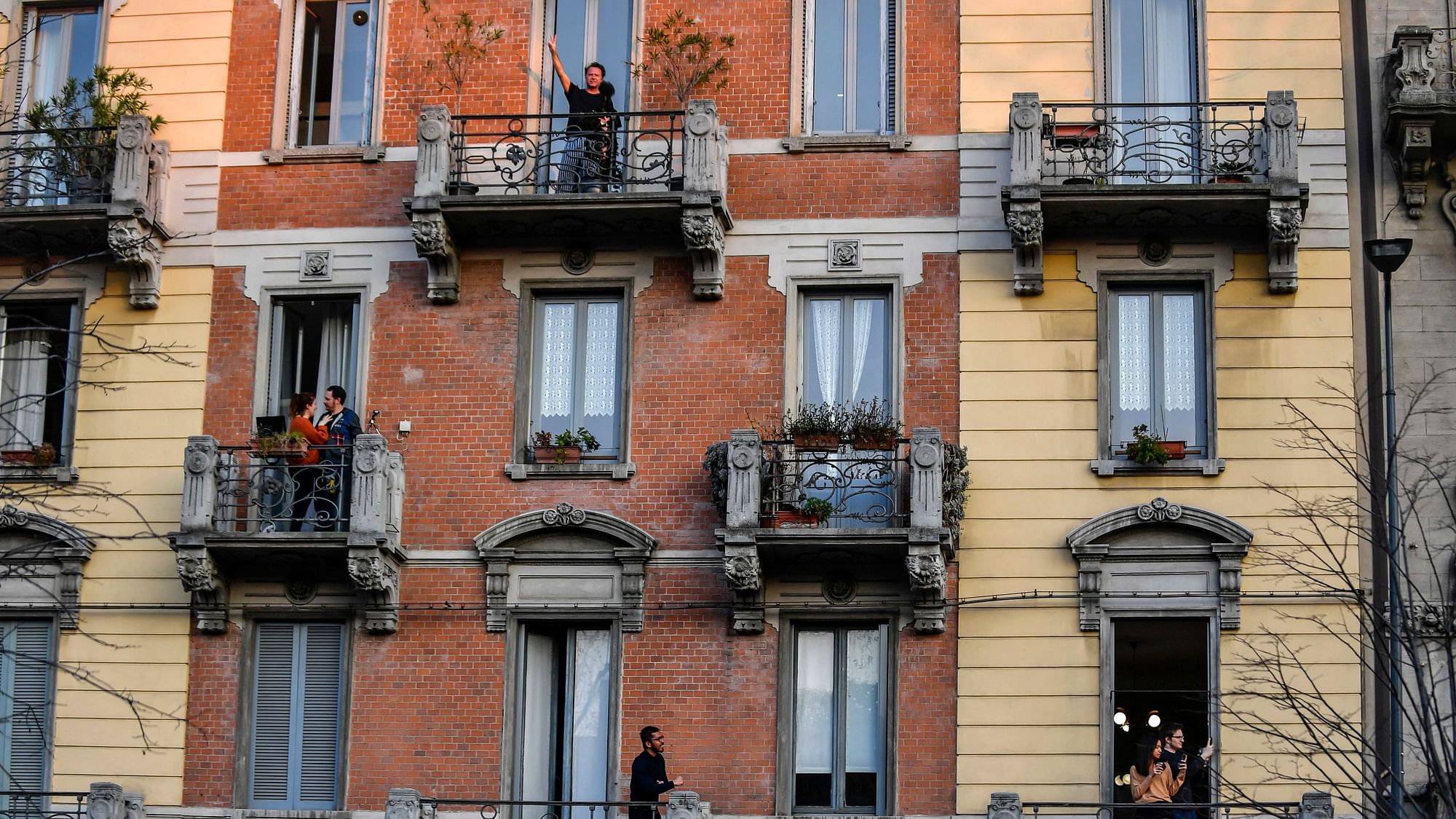 People stand on their balconies during one of the many flash mobs taking place these days in Milan, Italy, Sunday, 15 March 2020.