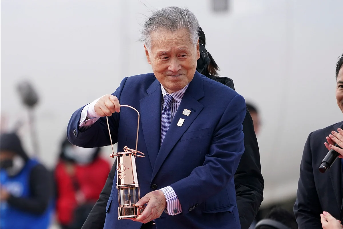 In this March 20, 2020, file photo, Tokyo 2020 Olympics chief Yoshiro Mori carries the Olympic flame during the Flame Arrival Ceremony at Japan Air Self-Defense Force Matsushima Base in Higashimatsushima.