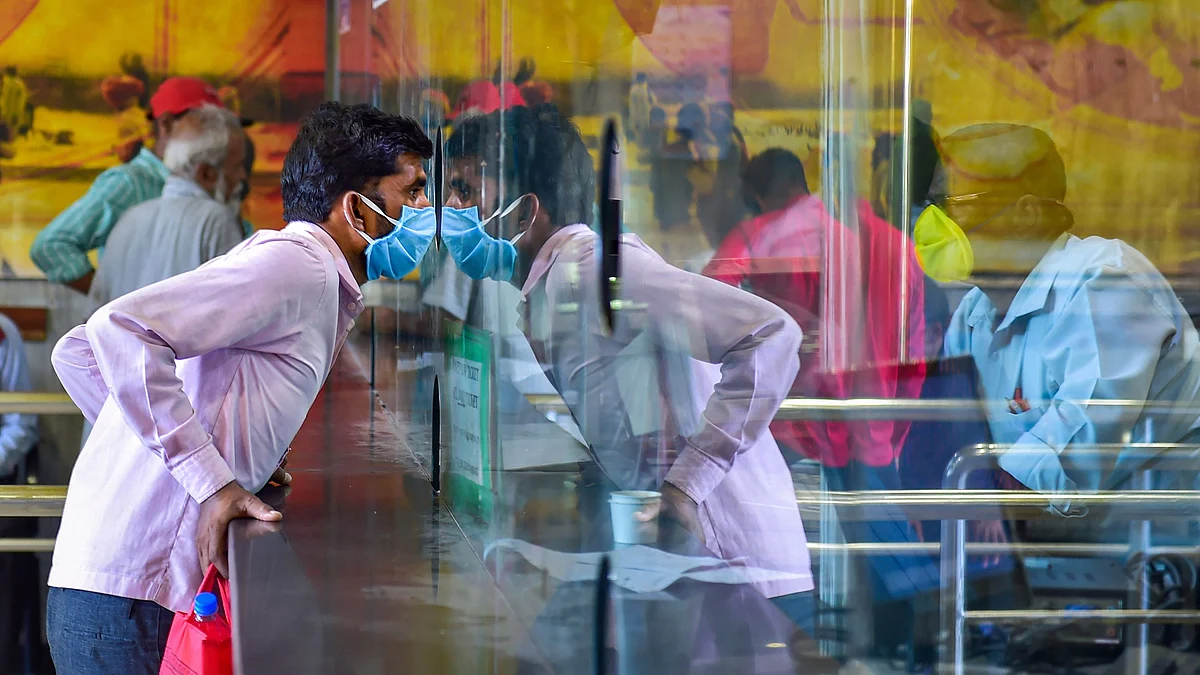 A passenger, wearing a mask in the wake of coronavirus (COVID-19) pandemic, speaks to a railway official at an enquiry counter, at Bengaluru City Railway Station, Monday, 16 March 2020.