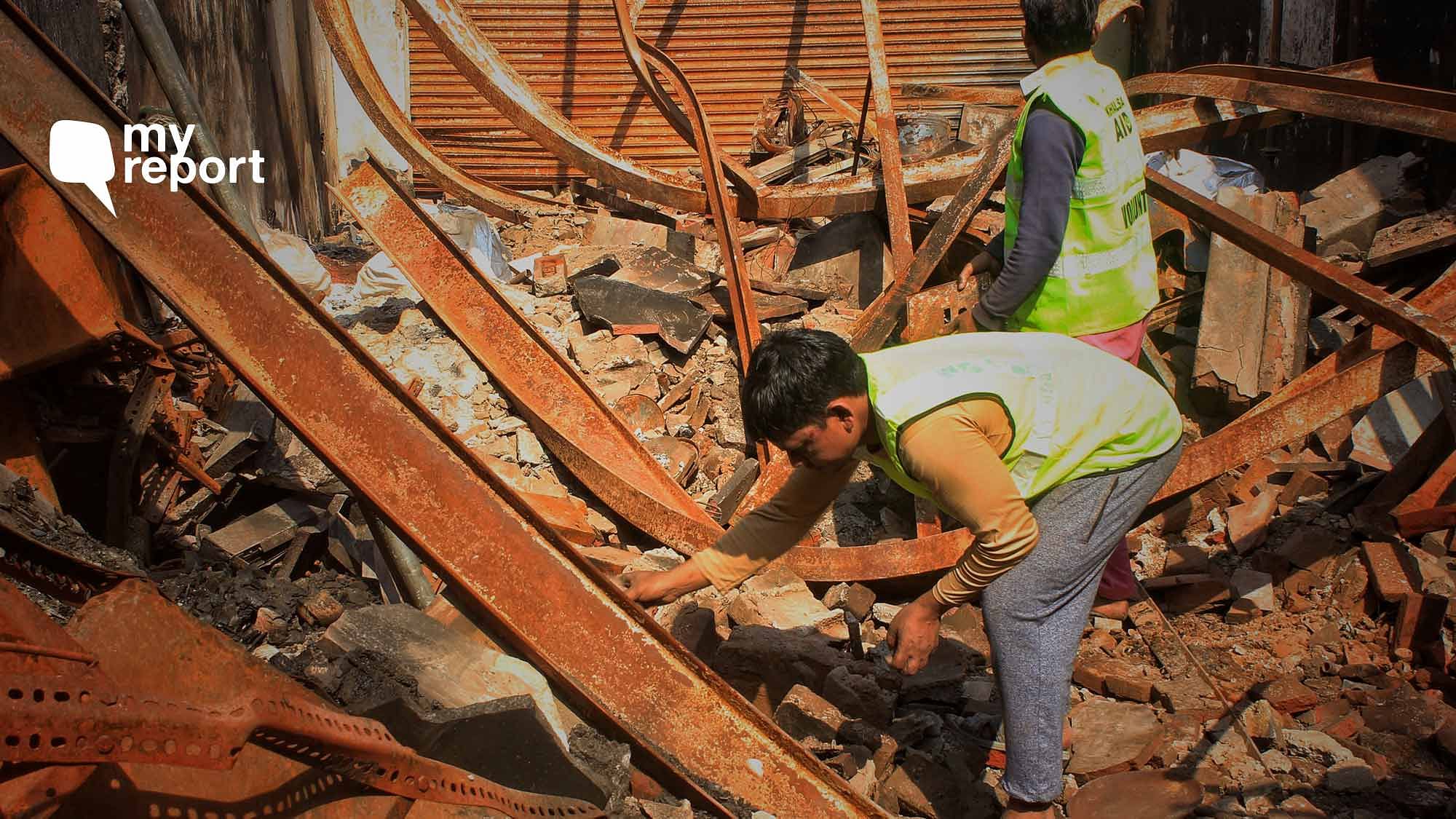 Workers clear rubble at a shop that was vandalised.&nbsp;
