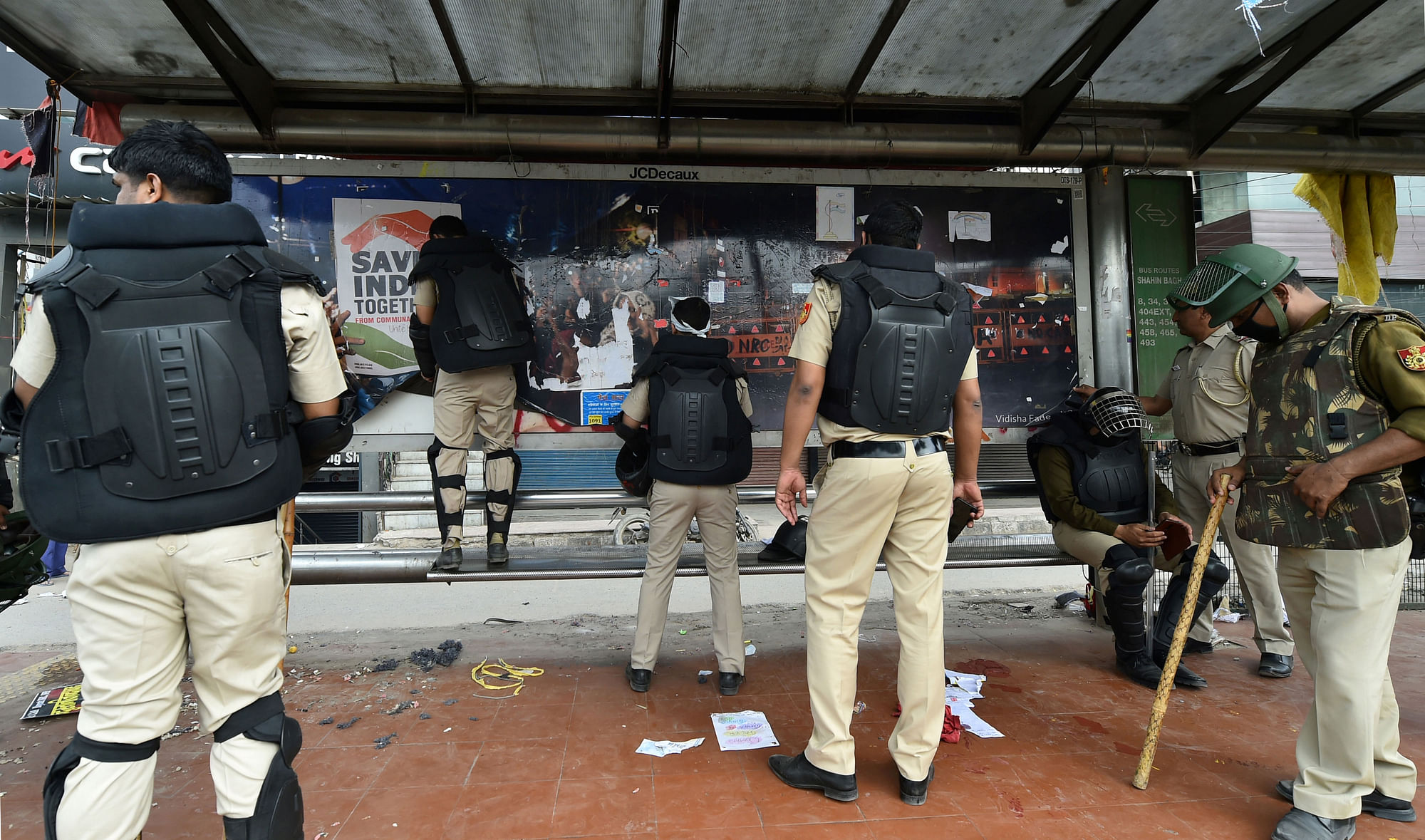 Delhi Police personnel remove posters at Shaheen Bagh protest site.