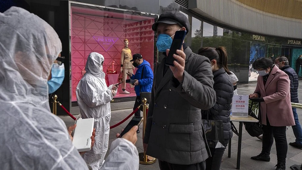 Workers wearing protective suits check customers’ health QR codes at the entrance of a re-opened shopping mall in in Wuhan in central China’s Hubei province, Monday, 30 March 2020.