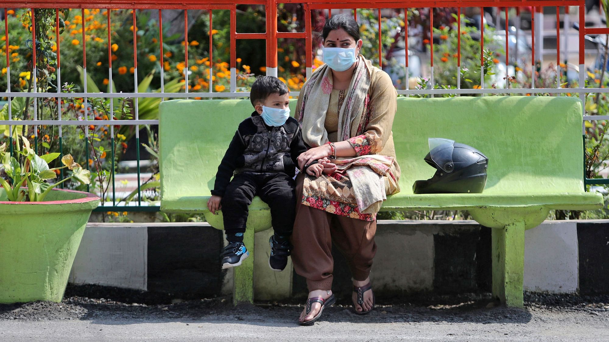 An Indian woman and a child wearing masks sit outside Government Medical College hospital in Jammu, India, Sunday, March 8, 2020.