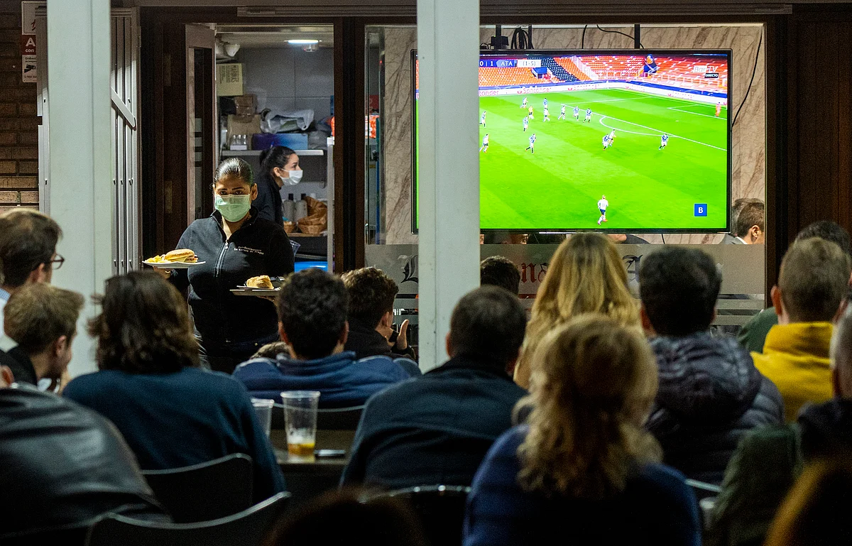 In this Tuesday March 10, 2020 filer, waiters wearing masks serve food and drink in a terrace outside Mestalla stadium during the Champions League round of 16 second leg soccer match between Valencia and Atalanta in Valencia, Spain.