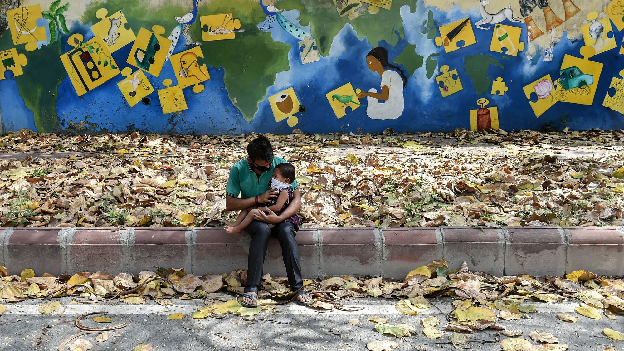 A man takes care of a child while sitting on a pavement during ongoing COVID-19 lockdown in New Delhi, Sunday, 19 April , 2020.&nbsp;