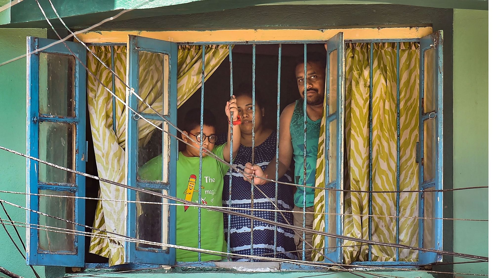 A family looks from the window of a house during the lockdown imposed to contain the coronavirus pandemic, in Kolkata, Tuesday, 31 March. Representational image.&nbsp;