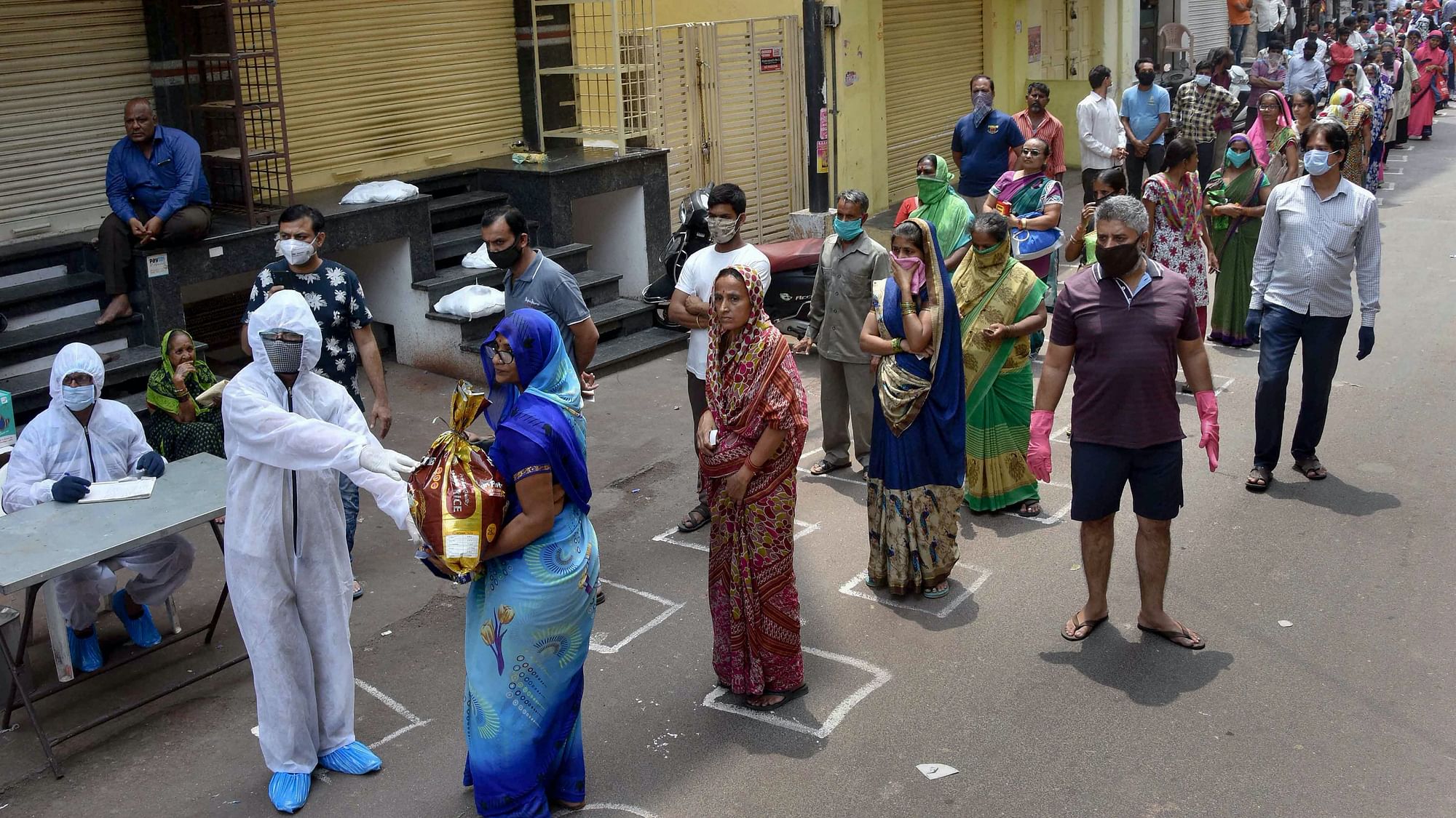 NGO workers distribute relief material among needy people during a nationwide lockdown, imposed in the wake of coronavirus pandemic, at Begum Bazaar in Hyderabad, Friday, 3 April.