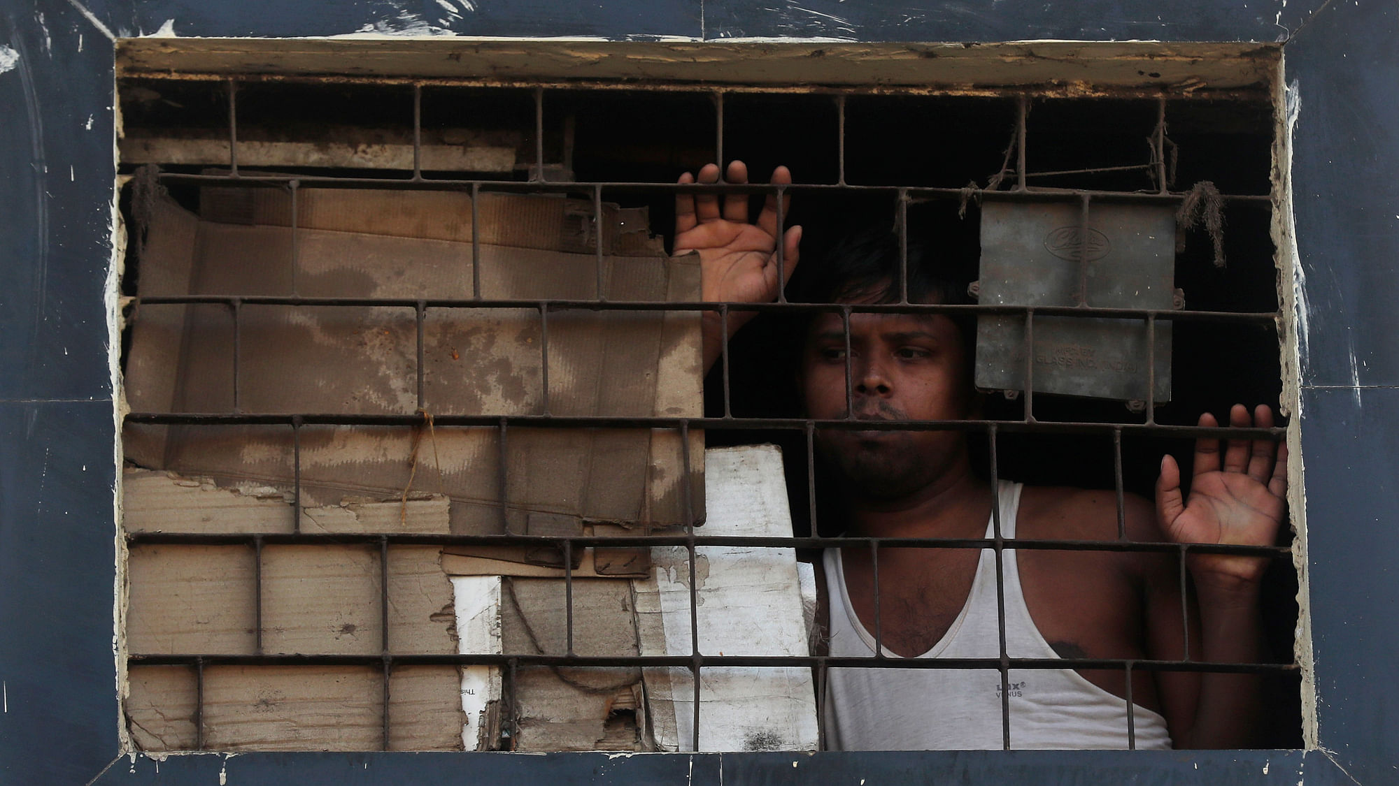 A migrant worker watches through the window of his room as police patrol in Dharavi, one of Asia’s largest slums, during lockdown.