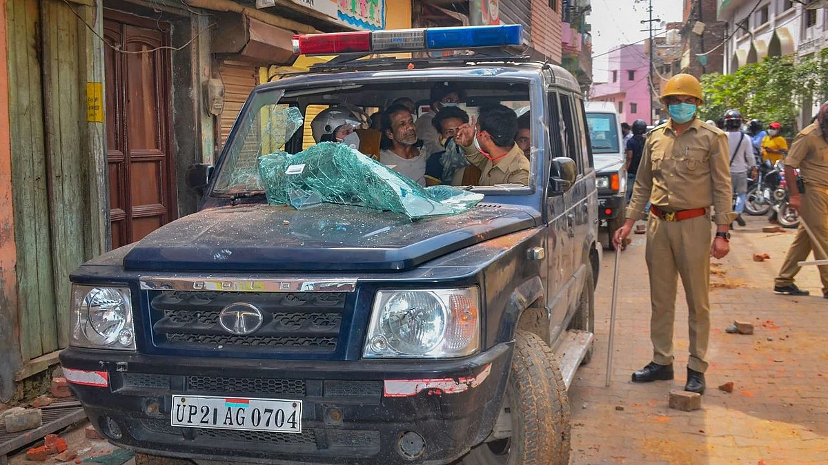 A team of medical personnel and police along with a patient sit inside a vandalised ambulance after a mob attacked their vehicle with stones.