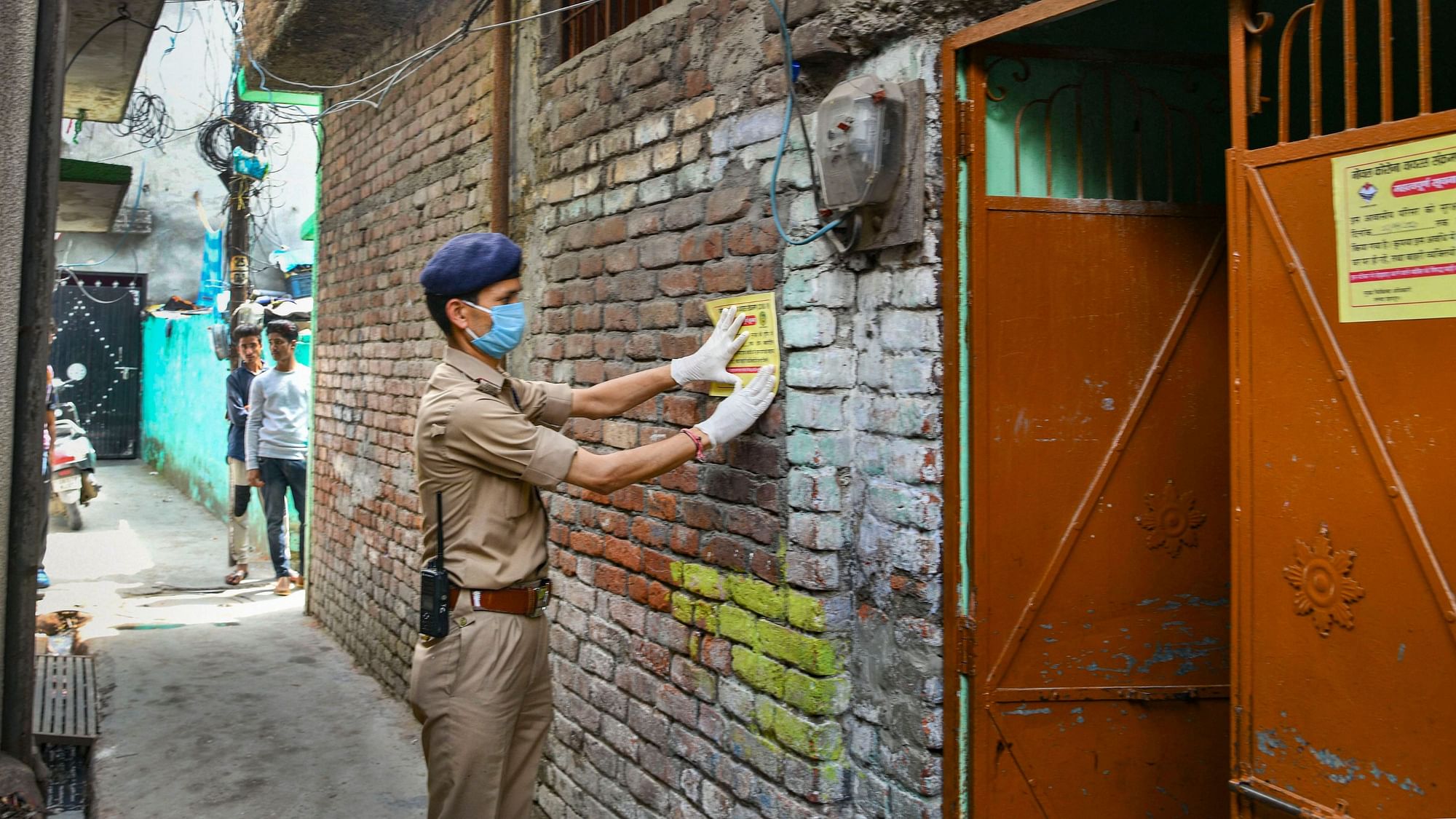 A policeman pastes a notice at the residence of a COVID-19 positive muezzin (who recites prayer-call at mosques) after he along with his family members was taken for quarantine, in Dehradun, Tuesday, 7 April 2020.