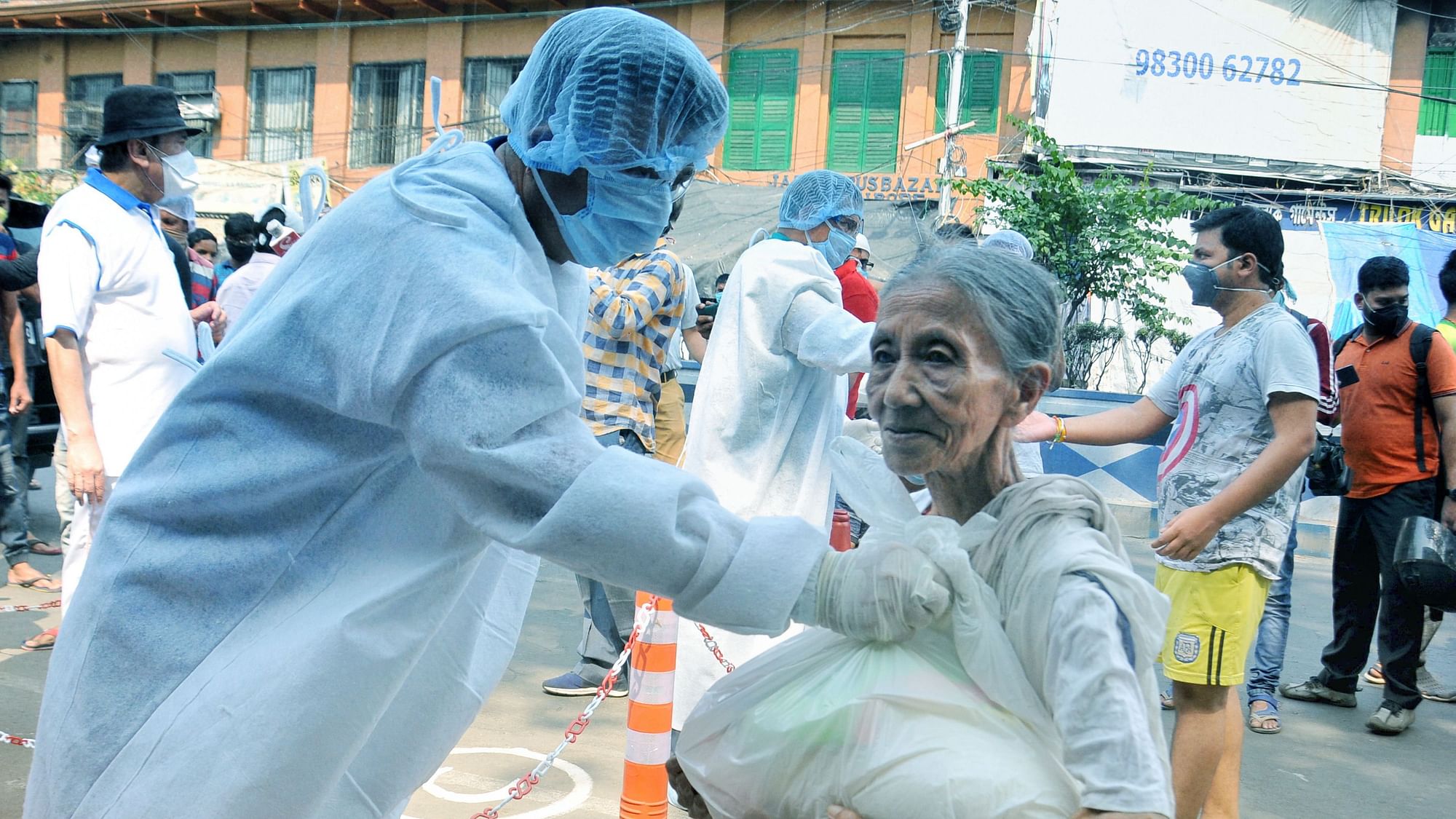 Volunteers wearing protective suits distribute essential items among the needy during the ongoing COVID-19 lockdown, in Kolkata, on Saturday, 4 April.