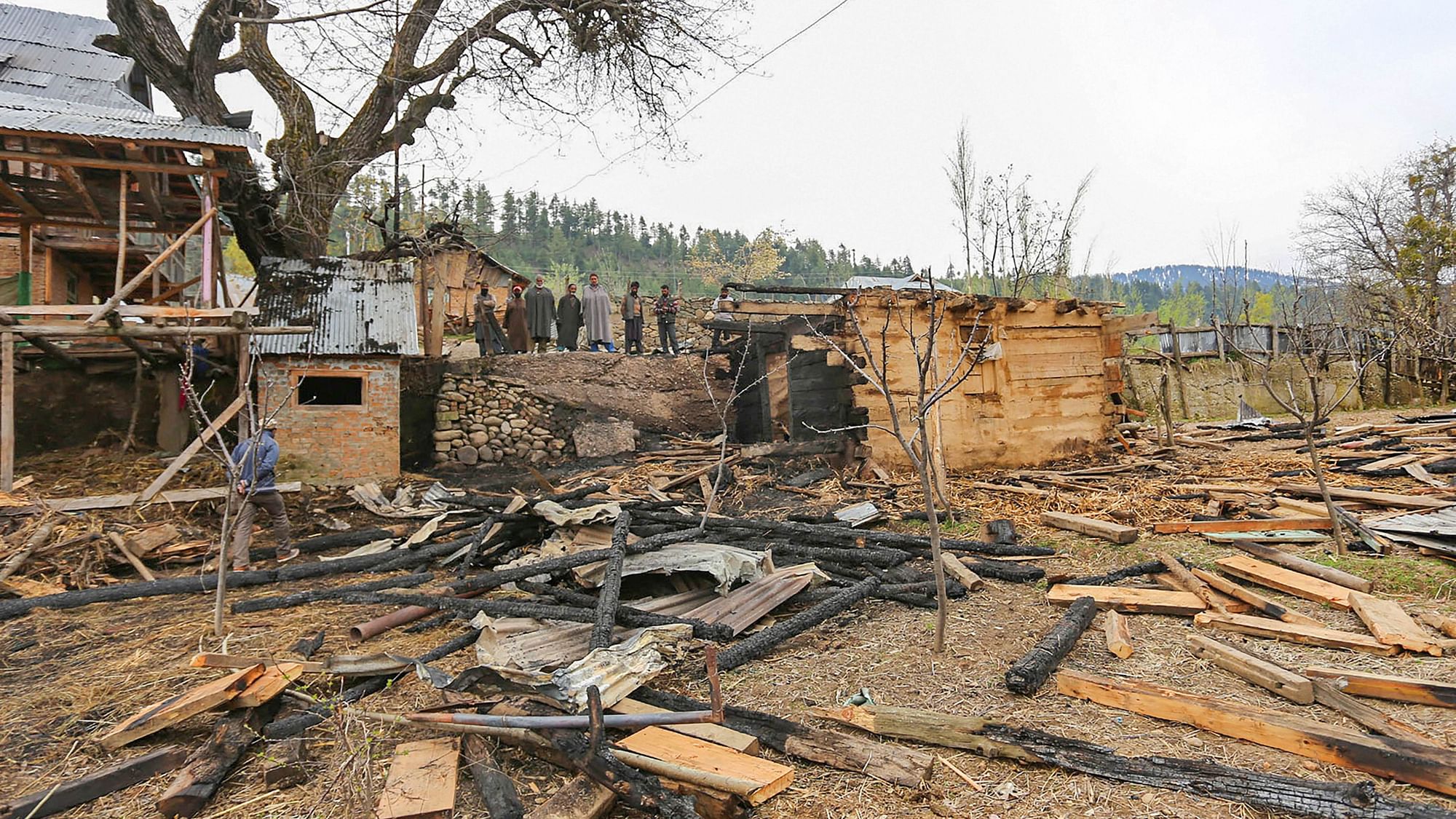 Locals look at the damaged properties following the ceasefire violation by Pakistani troops on Monday, 13 April.