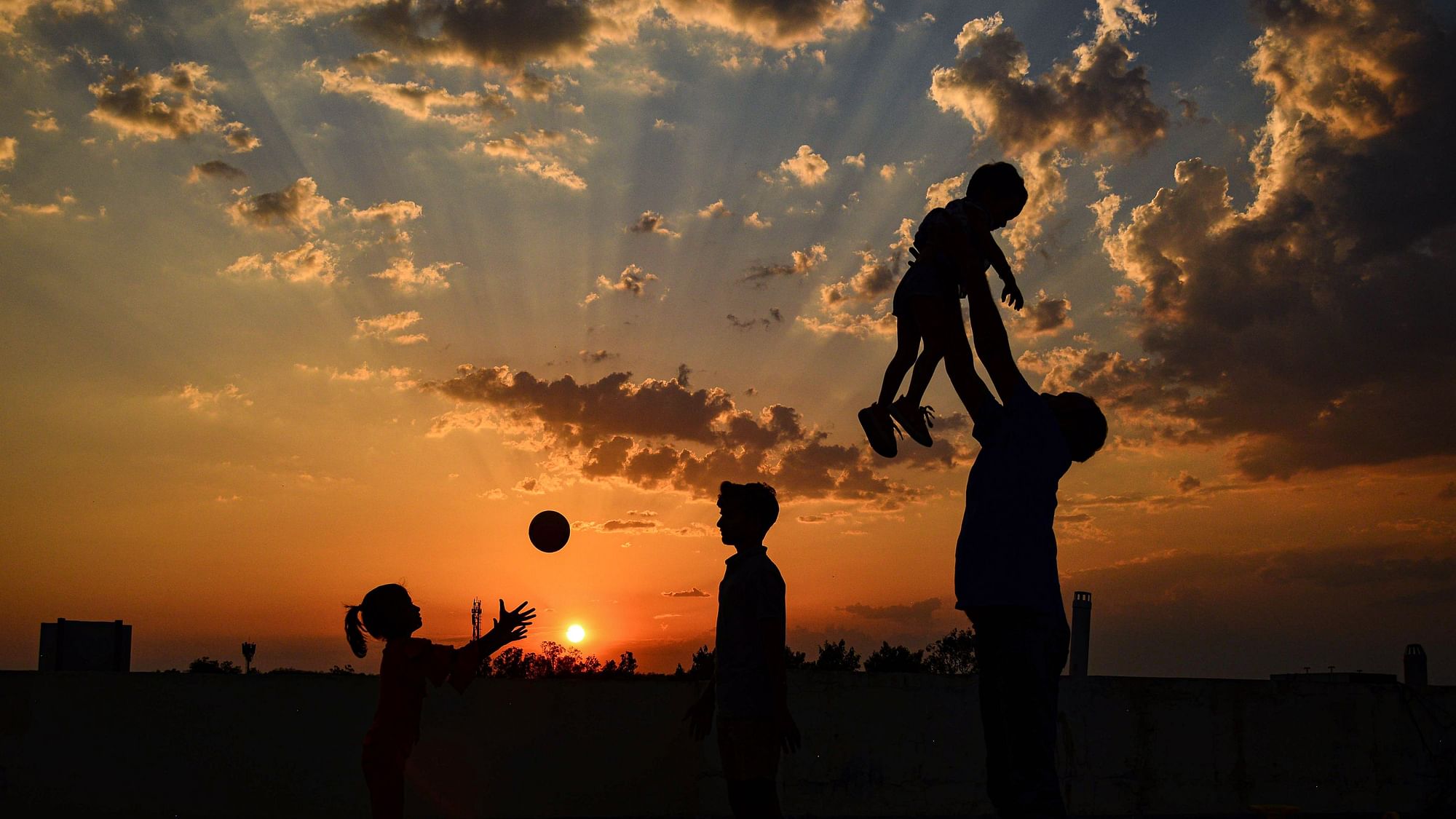 Members of a family are silhouetted against the setting sun as they play on the terrace of their house during the nationwide lockdown, in the wake of coronavirus pandemic, in Jabalpur on Tuesday, 31 March. 