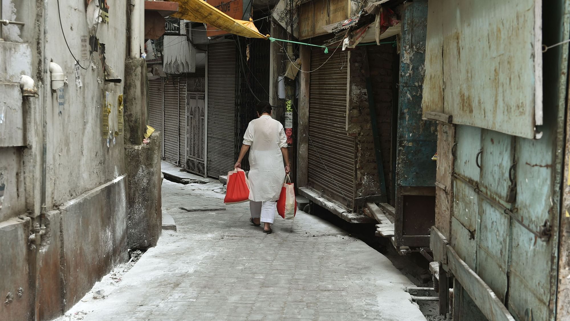 A man walks back to his residence after collecting essential supplies from a delivery person in a sealed area of Aminabad, where a COVID-19 case was detected yesterday, in Lucknow, Wednesday, 15 April, 2020.