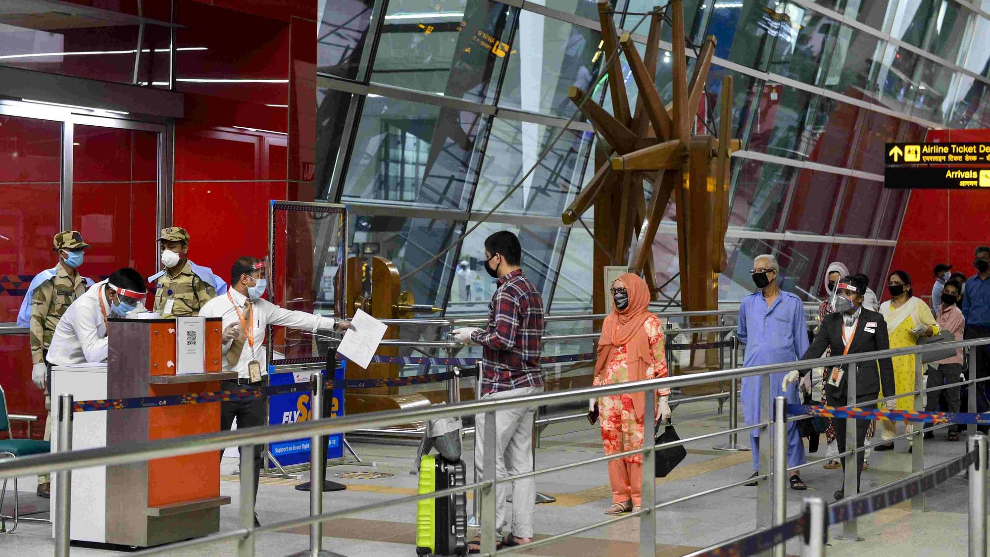 Passengers stand in a queue as they arrive at T-3 airport for domestic travel in New Delhi on 25 May.