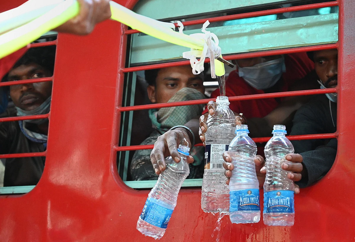 Railway employees provide water to migrants travelling in trains in Jabalpur, Thursday.