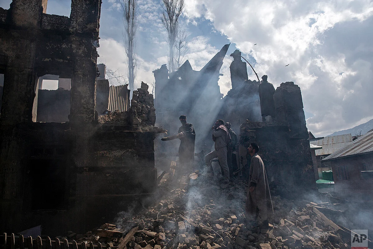 Kashmiri men dismantling a house destroyed in a gun battle in Tral village.