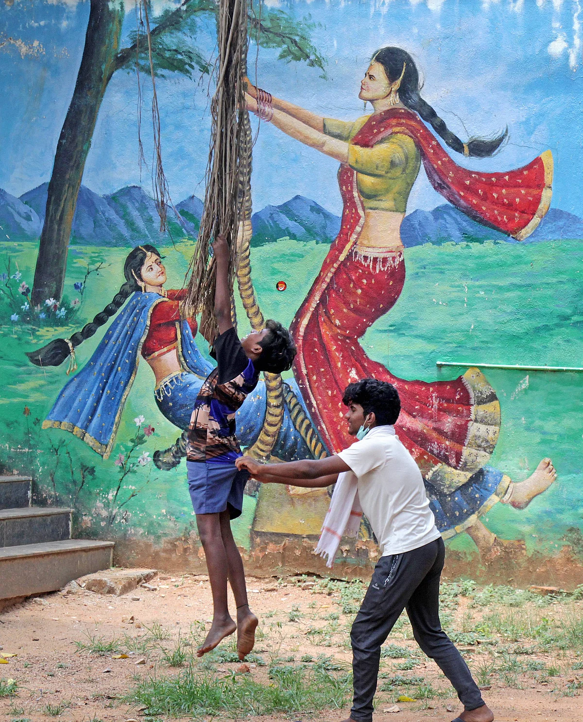 Children play in front of a mural painted on a wall, during ongoing lockdown in Bengaluru, Thursday.