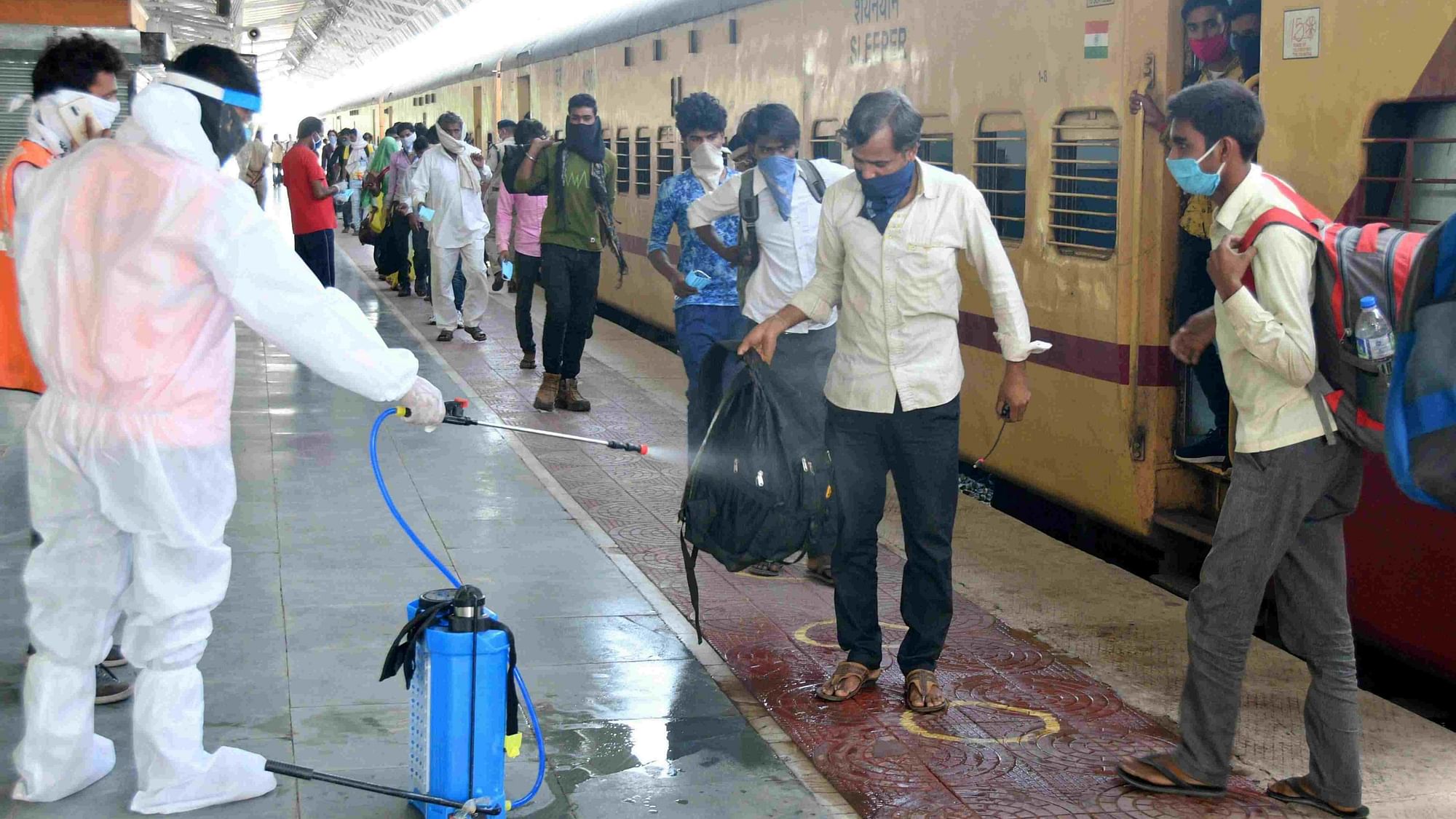 A worker sanitises the luggage of migrants who arrived from Mangalore by a shramik special train at the Jodhpur railway station on 16 May.