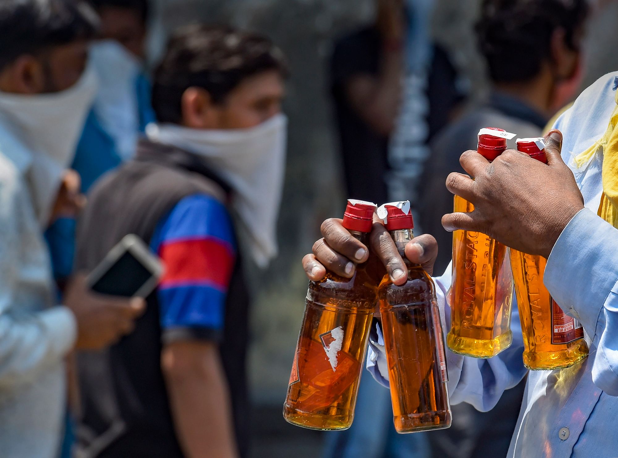 A man walks away after buying liquor from a wine shop that was opened amid COVID-19 lockdown after the authorities permitted sale of liquor with certain restriction, at Kalyanpuri in New Delhi, Tuesday, 5 May 2020. Long queues were witnessed outside liquor shops in Delhi despite imposition of 70 percent as coronavirus fee on the sale of liquor.