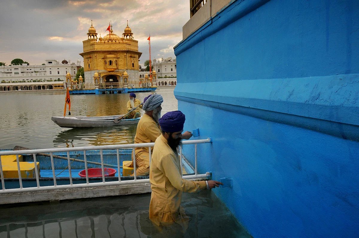 Sikh Sewadars (volunteers) paint the boundary of the Sarovar of Harmandir Sahib, also known as Golden Temple in Amritsar, Thursday.