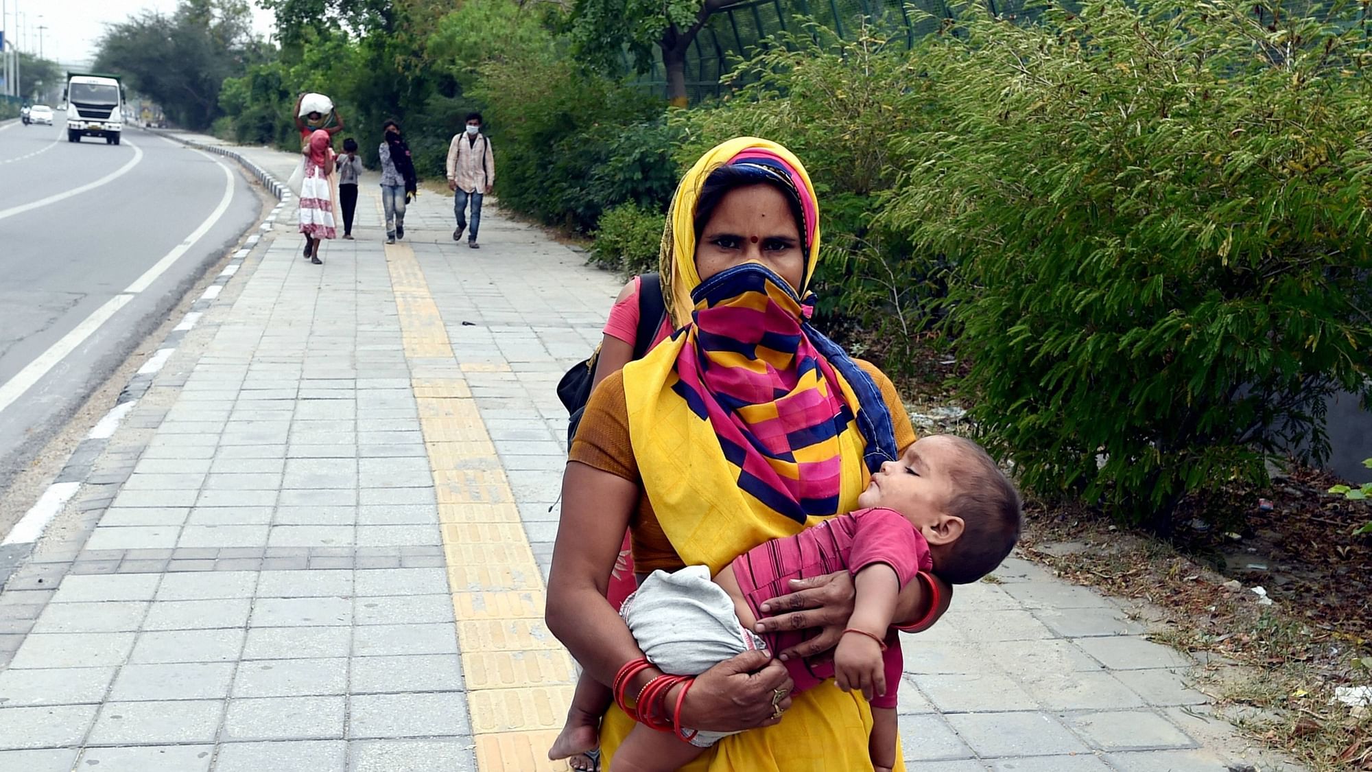 A migrant woman with her infant child travelling from Haryana walks towards her native place, during the ongoing COVID-19 nationwide lockdown, at Vivek Vihar in New Delhi, Wednesday, May 13, 2020.