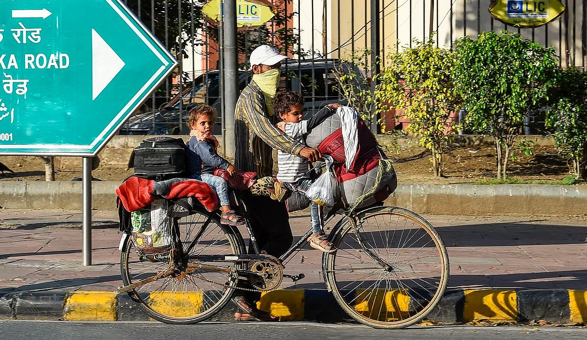 A migrant worker carries his family on a bicycle on his way to his native place, during the 21-day lockdown across the country to contain the COVID-19, in New Delhi, Friday, 27 March 2020.