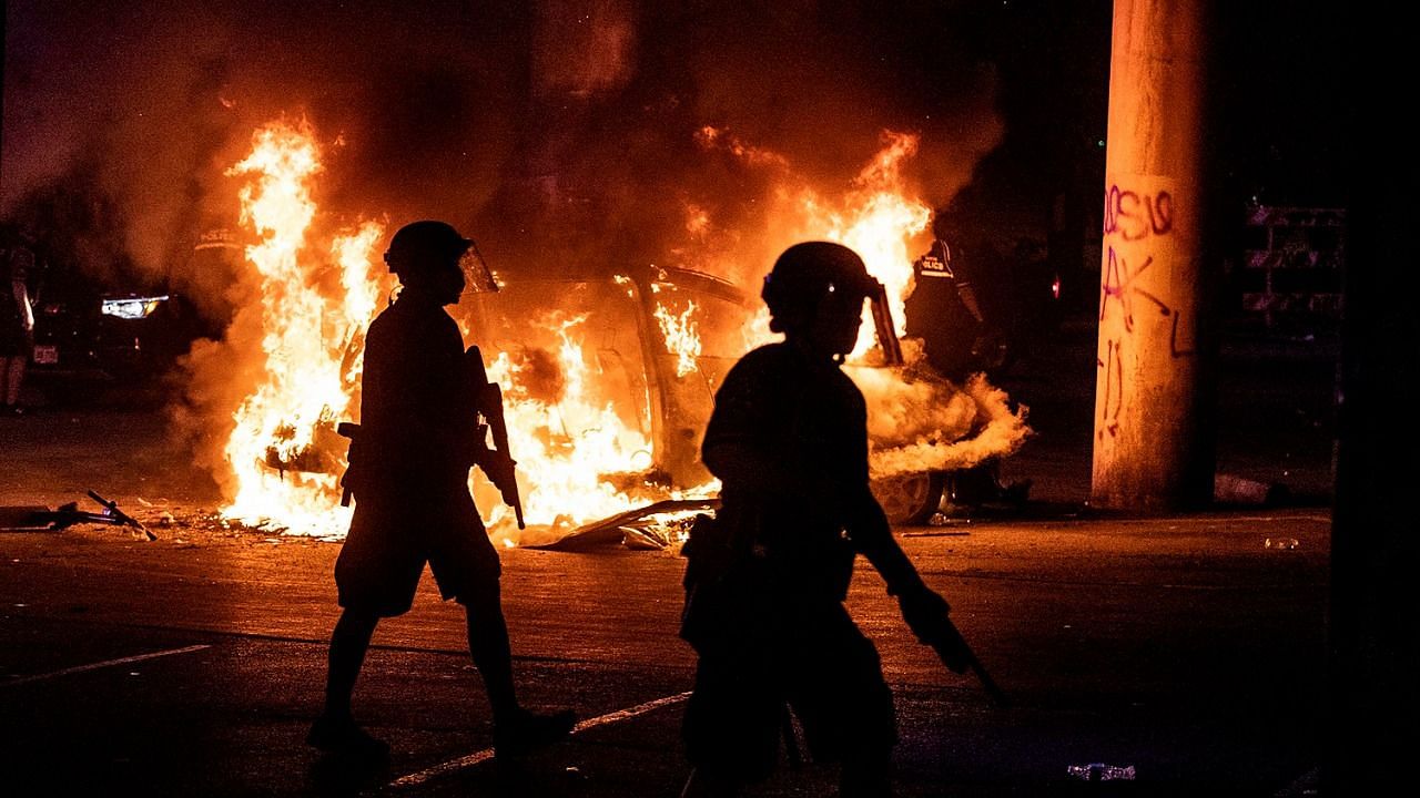 Police stand guard as Austin Fire Department put out a car on fire under Interstate 35 freeway in Austin Texas, Saturday, 30 May 2020, amid protests over the death of George Floyd, a handcuffed black man who died in Minneapolis police custody,