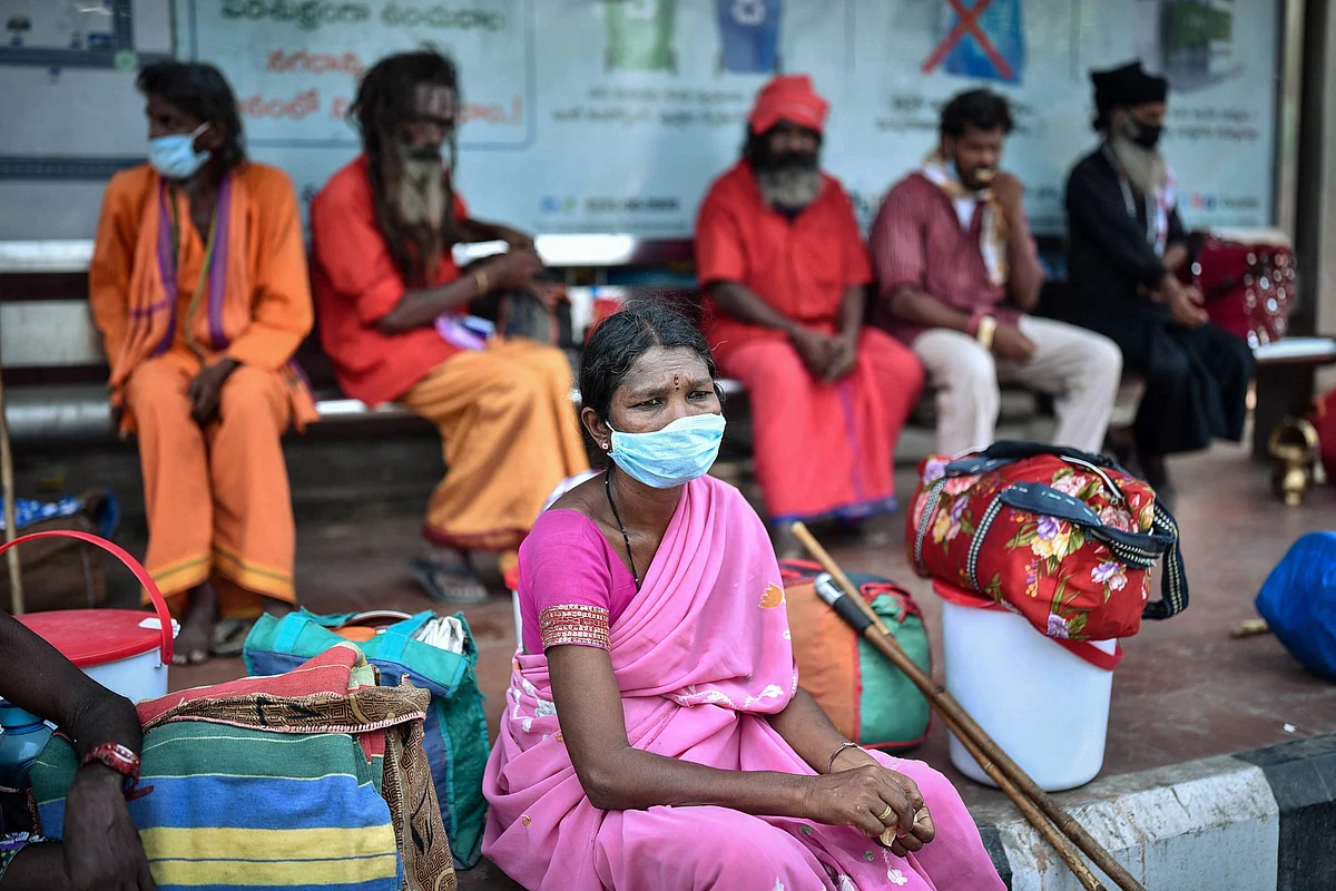 A woman waits at a bus stop to return to her native place in Vizianagaram after leaving a quarantine facility, in Vijayawada, Tuesday.