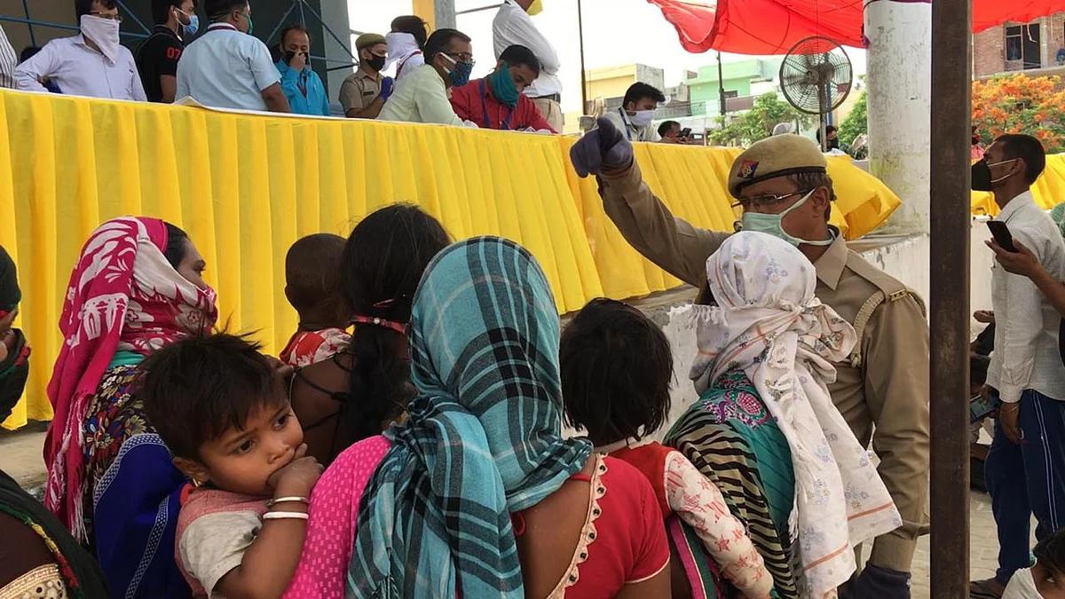 A group of women asking the policeman if there are buses to Bareily or Hathras, the policeman kept asking them to go on the side as there were no buses to where they lived.