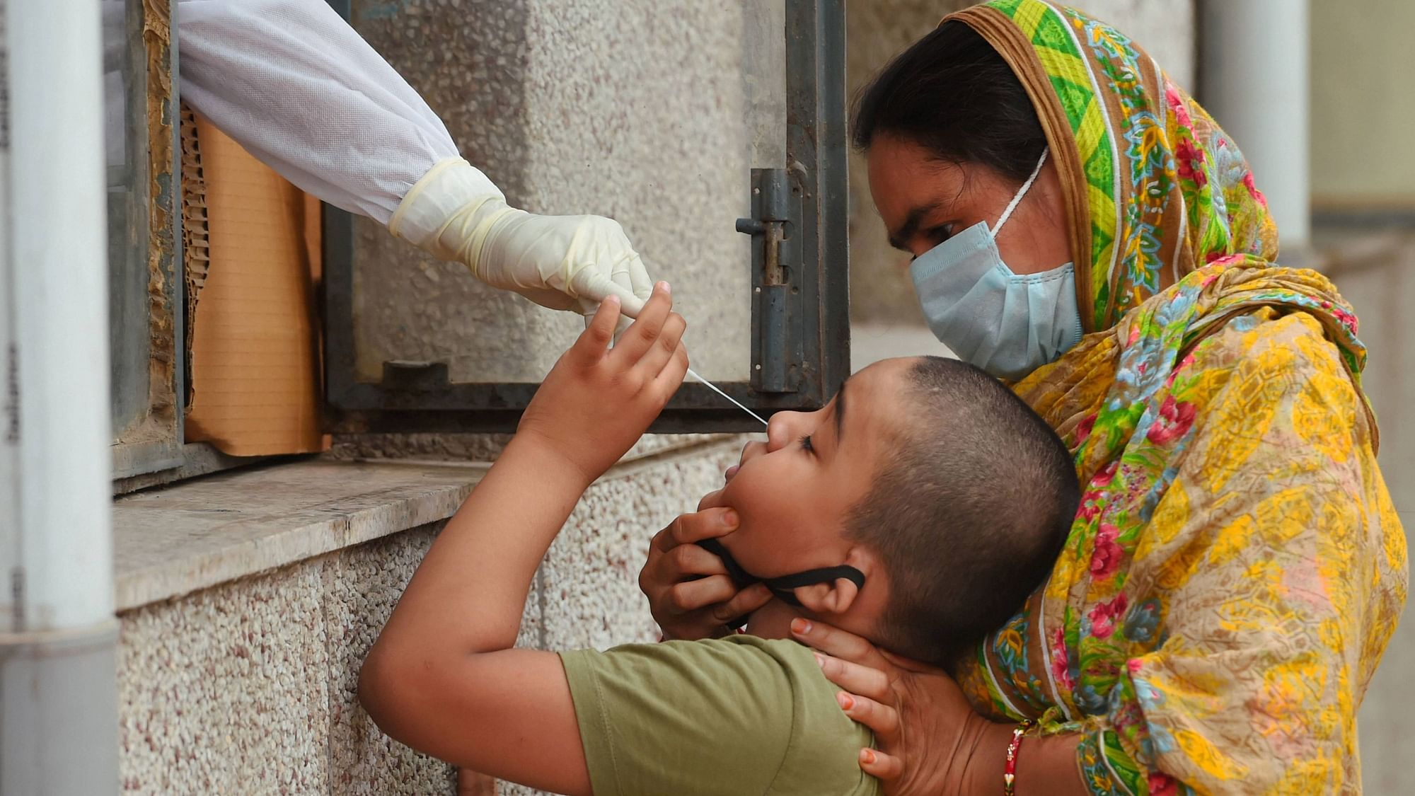 A medic takes swab samples of a boy for testing in Delhi.