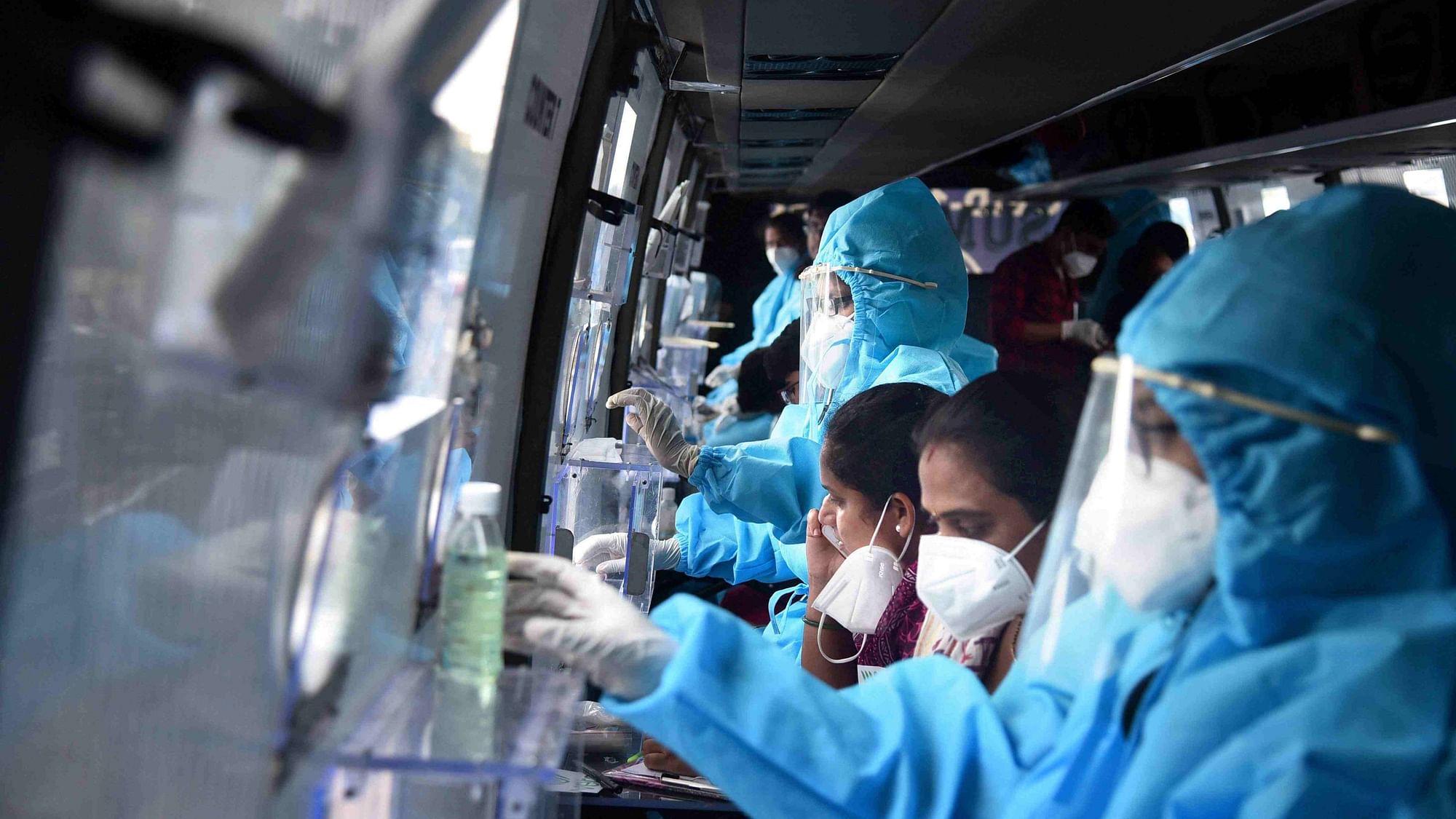 Healthcare workers prepare themselves to collect the swab samples of passengers returning to Vijayawada by Konark Express train, inside a mobile swab collection bus at Vijayawada Railway Station. Image used for representational purposes.&nbsp;