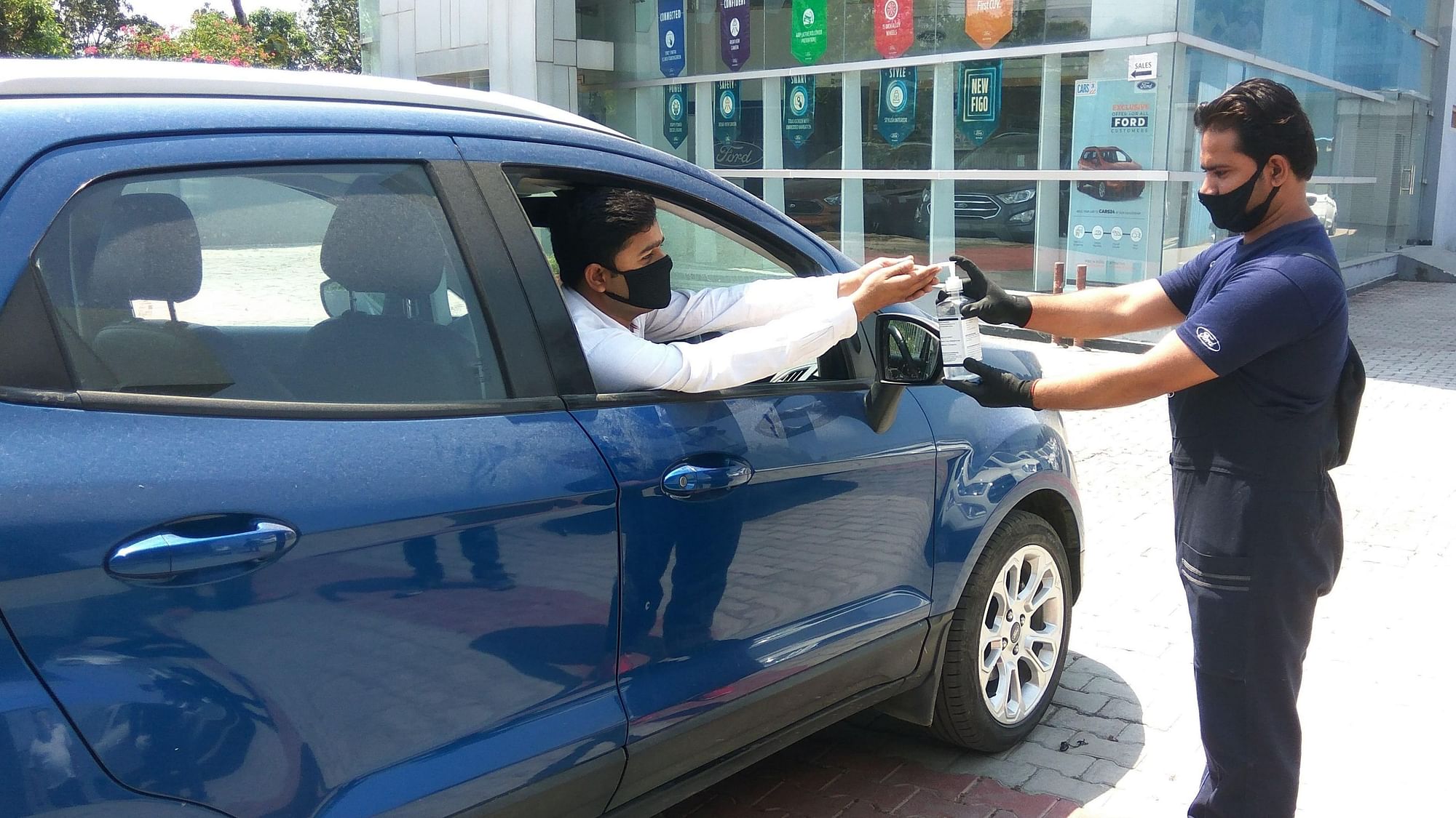 A customer taking a test drive at a Ford showroom sanitises his hands at the entrance.
