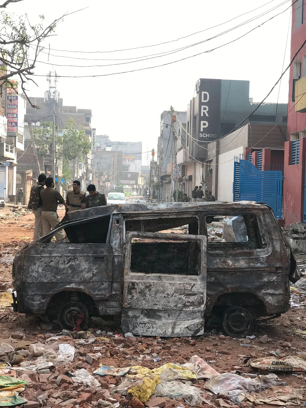 A school van stands in a pile of trash in front of DRP school in Shiv Vihar.