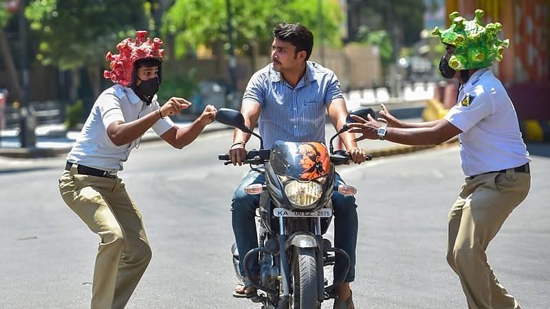 Two policeman wearing coronavirus-themed helmets charge another ríding a bike during an awareness programme amid the nationwide lockdown in the wake of novel coronavirus pandemic, in Bangalore.&nbsp;