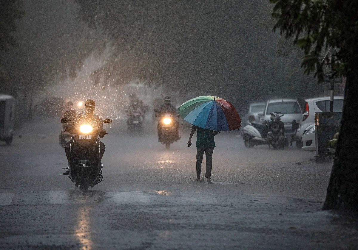 People seen commuting amid heavy rainfall, during the ongoing COVID-19 lockdown, in Ahmedabad.