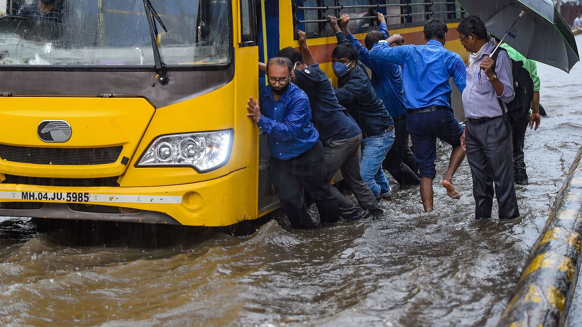 Locals push a school bus stuck in waterlogged street in Sion, Mumbai on 14 July.