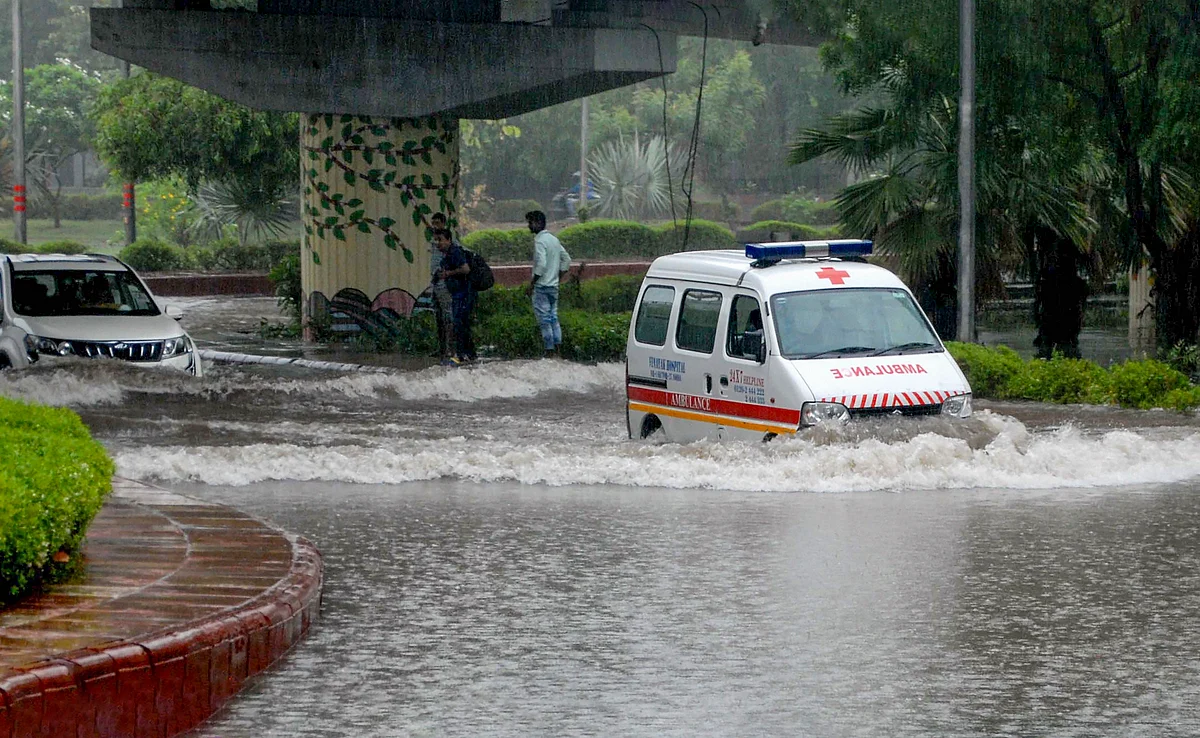 An ambulance wades through a waterlogged road after heavy rains, in Noida.