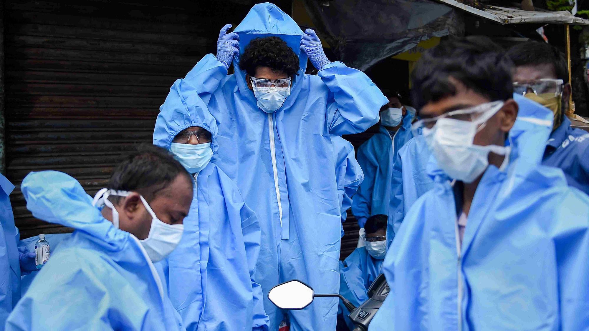 Health workers wear PPE kits before conducting medical check-up of residents of Kurar village, at Malad (East) in Mumbai on 13 July.