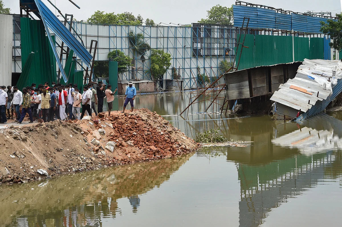 Locals look on at the site of a building collapse, due to monsoon rain, at Anna Nagar in New Delhi.