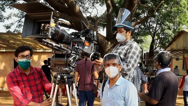 The cast and crew wear masks while shooting for an ad. 