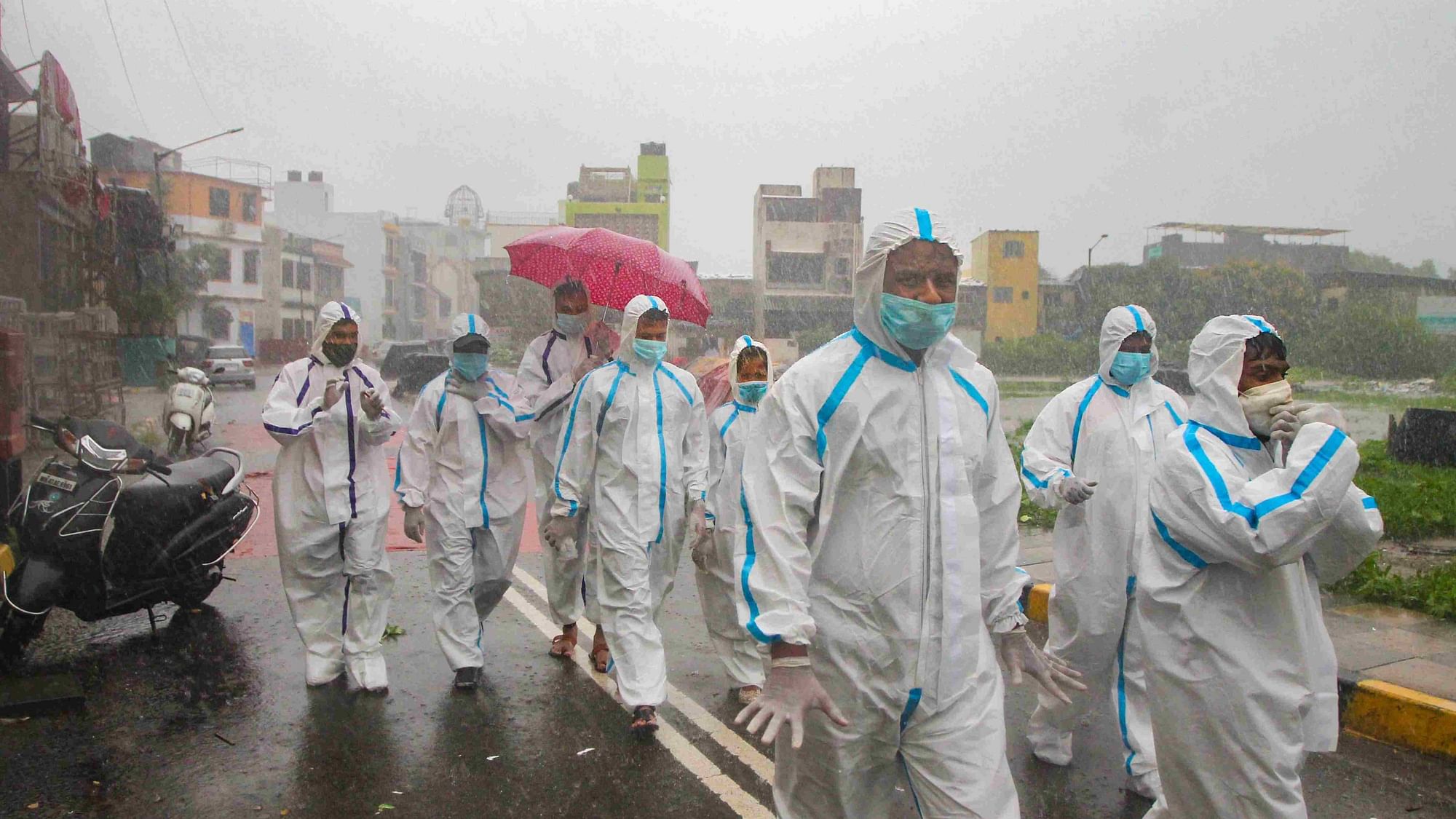Health workers wearing PPE arrive for COVID-19 medical checkup at a containment zone during heavy rain at Malad in Mumbai.&nbsp;