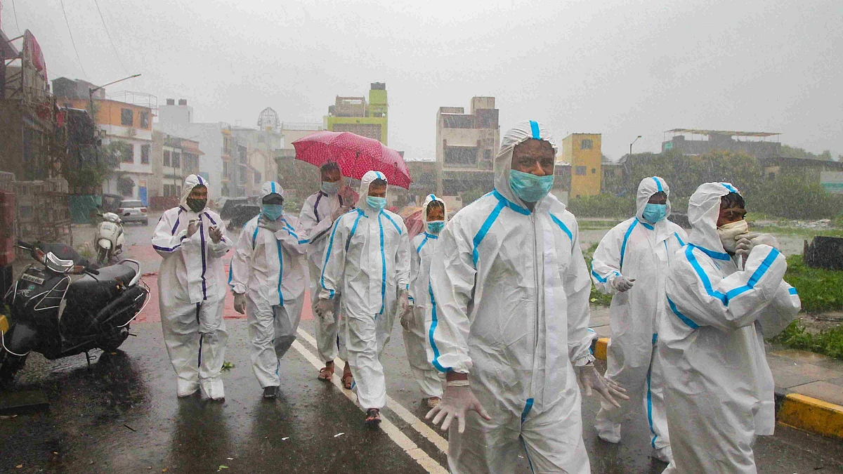 Health workers wearing PPE arrive for COVID-19 medical checkup at a containment zone during heavy rain at Malad in Mumbai. 