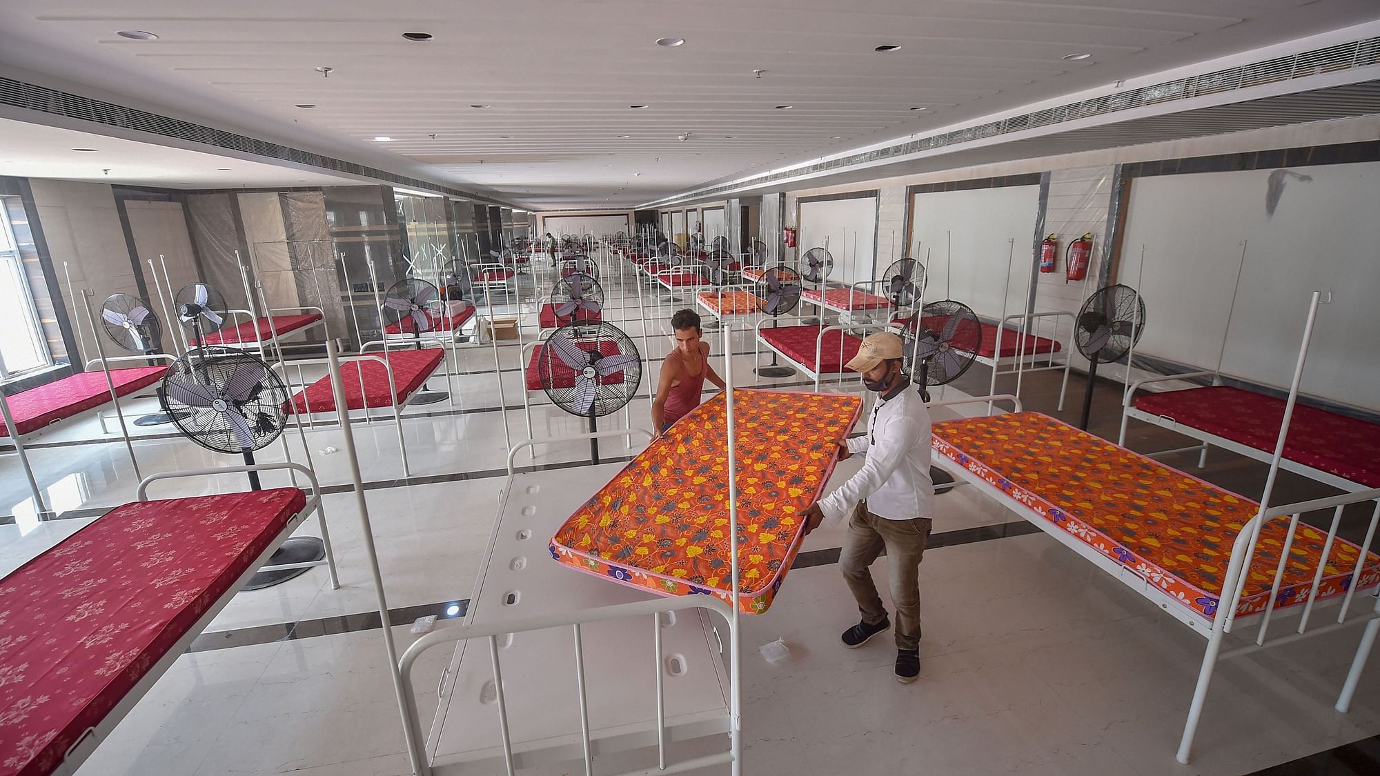 Workers set up beds in a gallery of Kishore Bharati Stadium for a makeshift COVID-19 care centre, in Kolkata, Tuesday, Aug 25, 2020. 