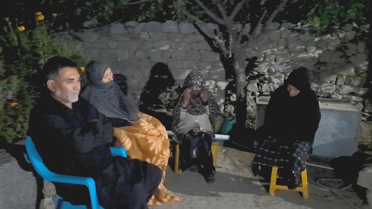 Family sitting in lawn of their house listening to majlis through loudspeakers 